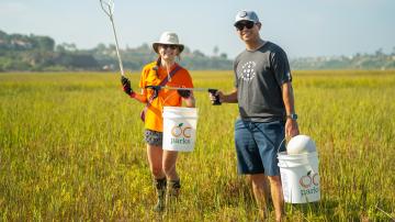 Two volunteers pick up trash at Coastal Cleanup Day at Upper Newport Bay.