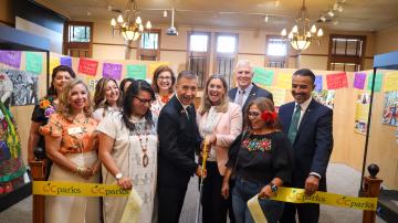 Group of city and county officials cut the ribbon to open a new art exhibit at the Old Orange County Courthouse.