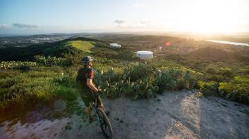 Biker overlooks hills in the distance as the sun sets.