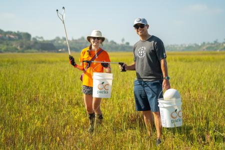 Two volunteers pick up trash at Coastal Cleanup Day at Upper Newport Bay.